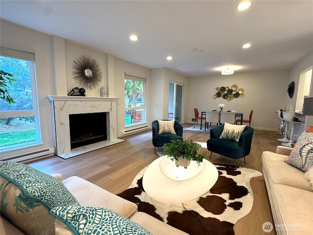 living area with recessed lighting, a baseboard radiator, wood finished floors, and a premium fireplace