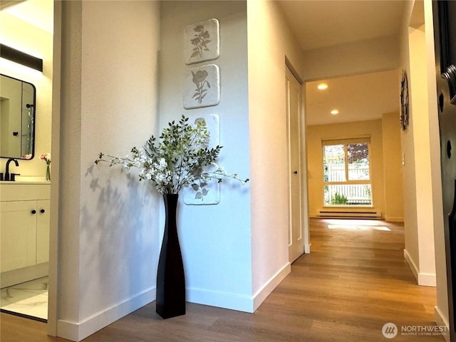 hall featuring baseboards, recessed lighting, and wood finished floors