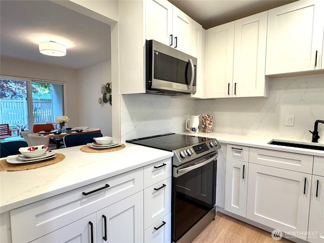 kitchen featuring a sink, white cabinetry, tasteful backsplash, and stainless steel appliances