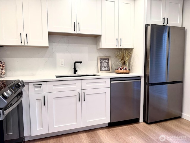 kitchen featuring light countertops, appliances with stainless steel finishes, a sink, and tasteful backsplash