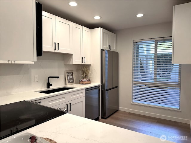 kitchen featuring a sink, appliances with stainless steel finishes, tasteful backsplash, and wood finished floors