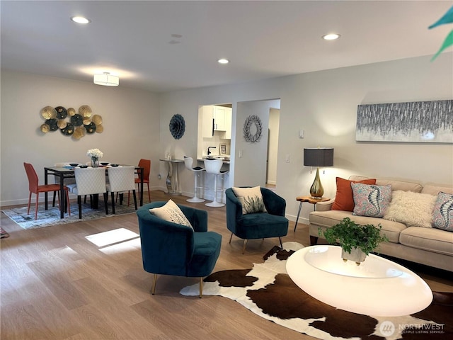 living area with recessed lighting, baseboards, and light wood-type flooring