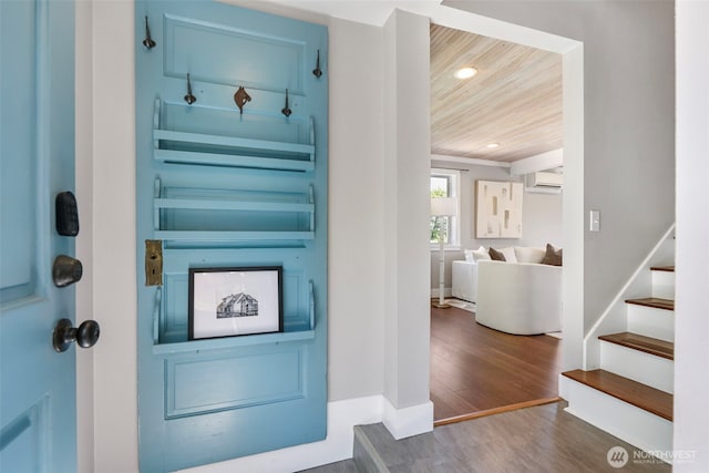 foyer with a wall mounted air conditioner, wood finished floors, stairs, wooden ceiling, and recessed lighting