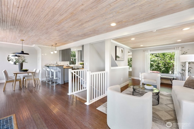living area featuring ornamental molding, wood finished floors, healthy amount of natural light, wooden ceiling, and baseboards