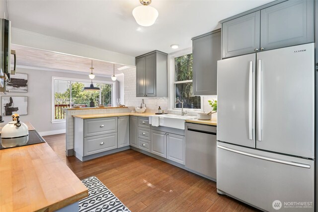 kitchen with freestanding refrigerator, gray cabinetry, dishwasher, a sink, and crown molding