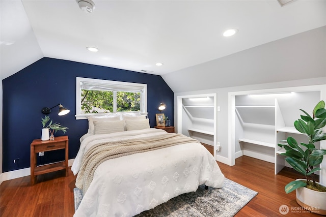 bedroom with vaulted ceiling, wood finished floors, and baseboards