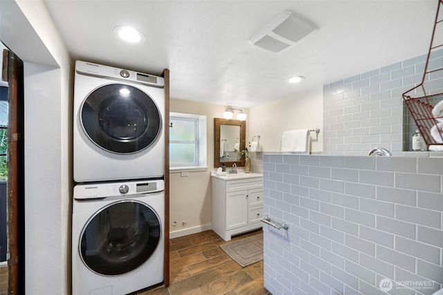 washroom with stacked washer / dryer and recessed lighting