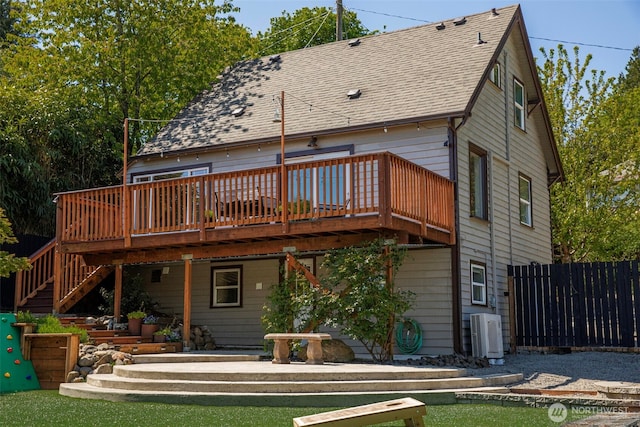 rear view of house featuring a wooden deck, fence, stairs, and a shingled roof