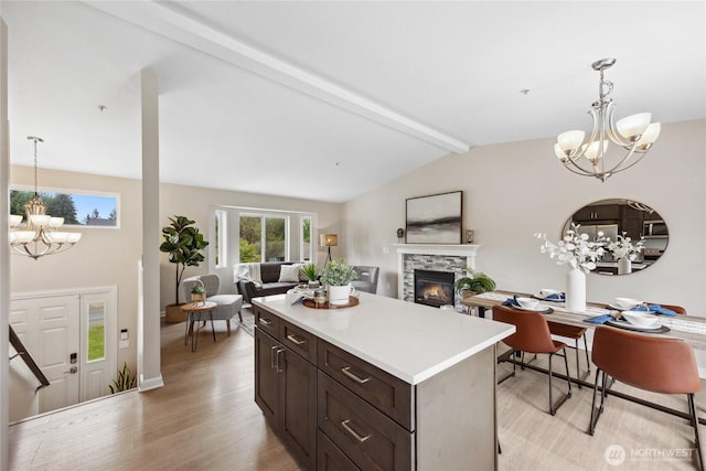 kitchen with a chandelier, light wood-style flooring, a fireplace, light countertops, and decorative light fixtures