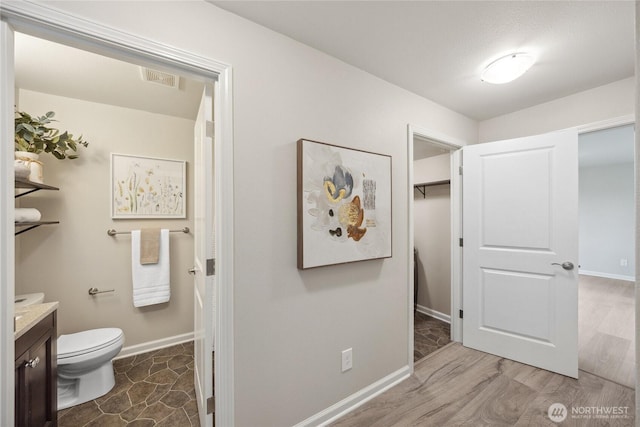 bathroom featuring vanity, baseboards, toilet, and wood finished floors