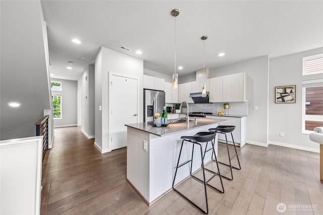 2055 NW Talus Dr Unit 3, Issaquah, WA 98027 - kitchen with stainless steel refrigerator with ice dispenser, under cabinet range hood, an island with sink, wood finished floors, and tasteful backsplash