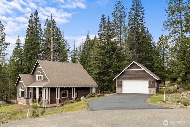 view of front of home featuring covered porch, an outbuilding, a garage, and stone siding