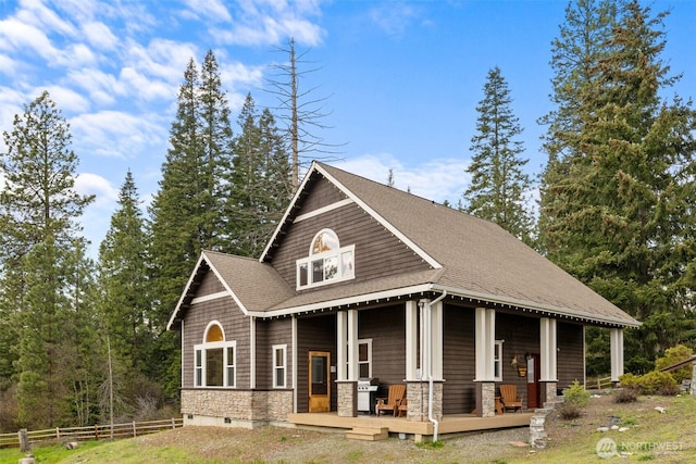 exterior space featuring fence, a shingled roof, and stone siding