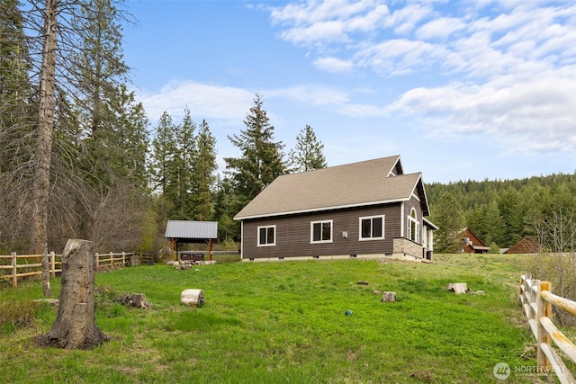 back of house featuring a yard, a forest view, fence, and crawl space