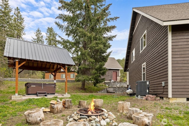 view of yard with central AC unit, a hot tub, and an outdoor fire pit