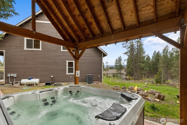 wooden terrace featuring a hot tub, fence, and central AC