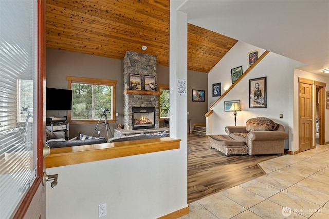 tiled living area with plenty of natural light, vaulted ceiling, a fireplace, and baseboards