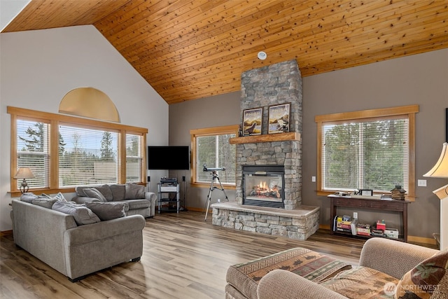 living room featuring high vaulted ceiling, a wealth of natural light, a stone fireplace, and wood finished floors
