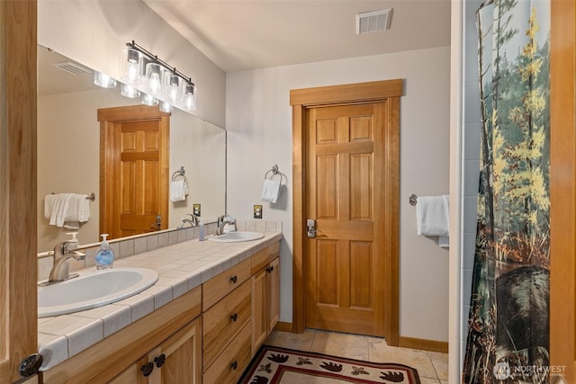 bathroom featuring a sink, tile patterned flooring, baseboards, and visible vents