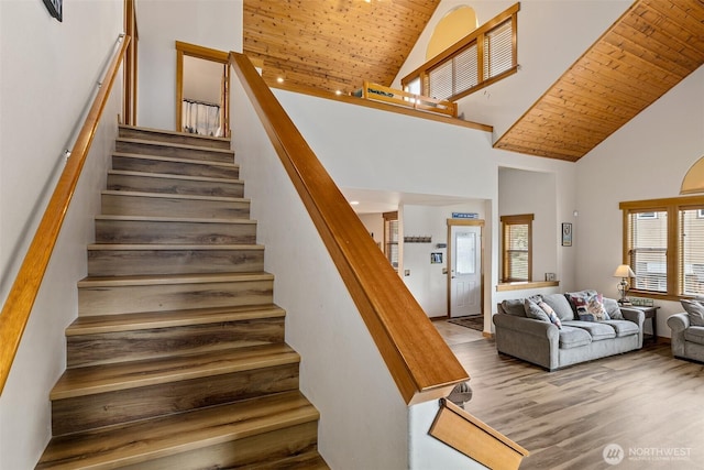 stairs with wooden ceiling, wood finished floors, and high vaulted ceiling
