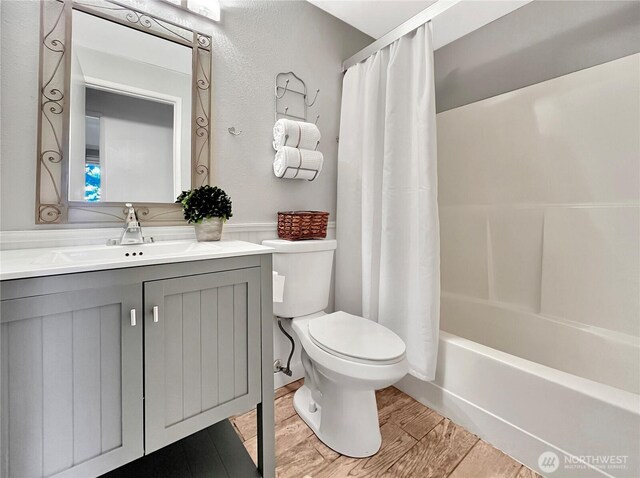 bathroom with vanity, wood finished floors, shower / bath combination with curtain, and toilet
