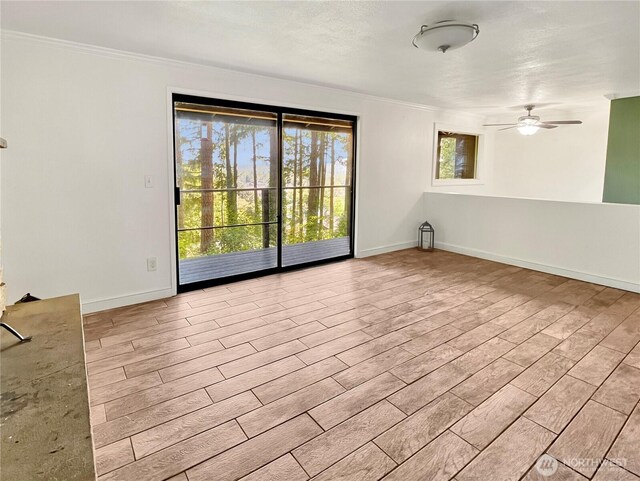 spare room with crown molding, light wood-style floors, ceiling fan, and baseboards