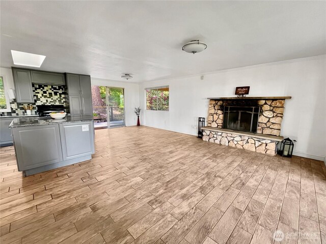 living room with light wood-style flooring, a fireplace, and a skylight