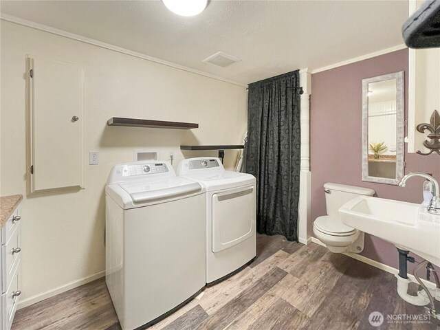 washroom featuring light wood-style floors, baseboards, laundry area, and washing machine and clothes dryer