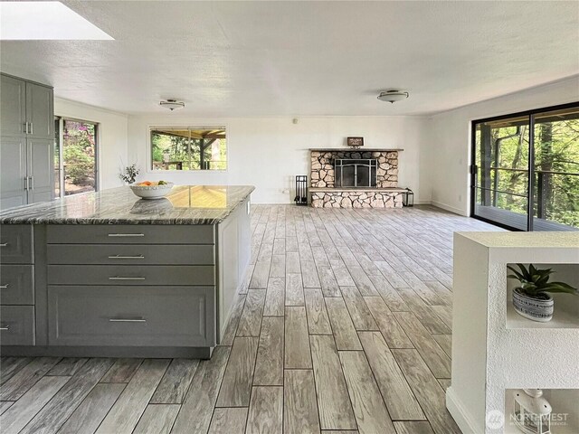 kitchen featuring light stone countertops, plenty of natural light, gray cabinets, and light wood-style flooring