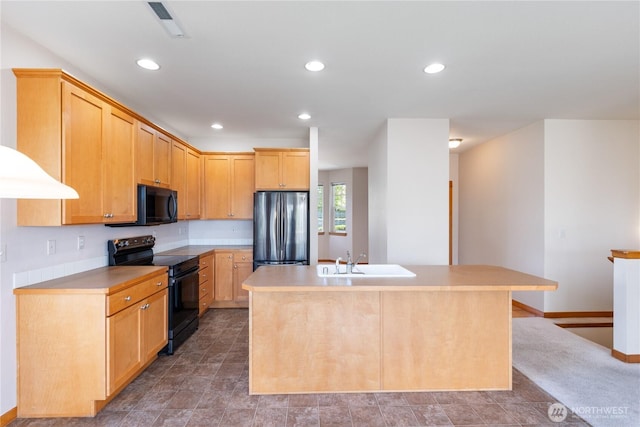 kitchen featuring light brown cabinetry, a sink, light countertops, black appliances, and an island with sink