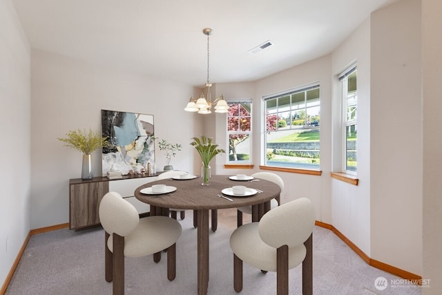 dining space with baseboards, light colored carpet, a chandelier, and visible vents