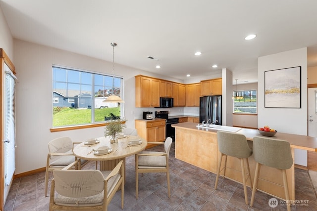 kitchen featuring stone finish floor, visible vents, light countertops, a sink, and black appliances