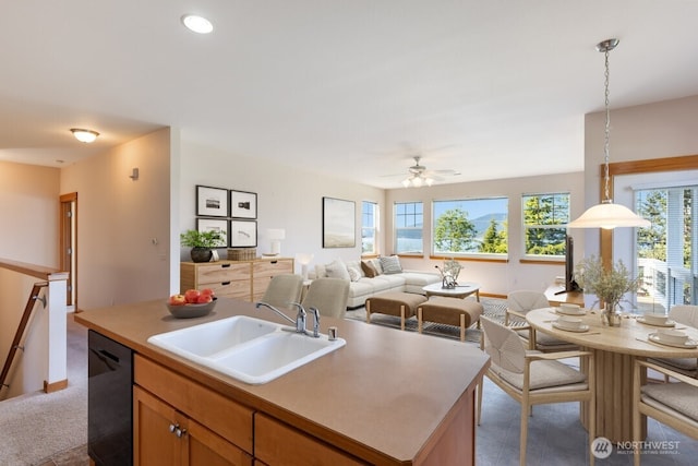 kitchen featuring a ceiling fan, decorative light fixtures, a center island with sink, dishwasher, and a sink