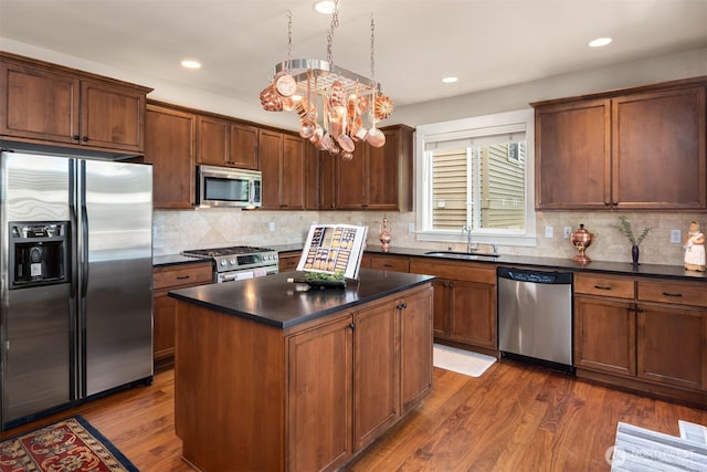 kitchen with a sink, dark wood finished floors, appliances with stainless steel finishes, and dark countertops