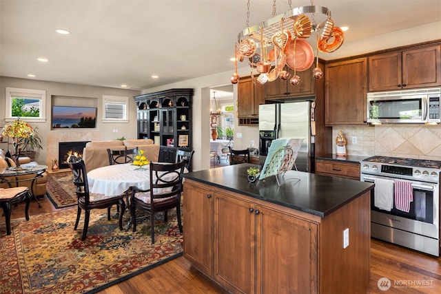 kitchen with backsplash, dark wood-style flooring, dark countertops, and appliances with stainless steel finishes