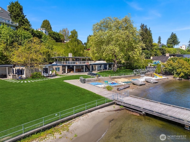 exterior space featuring a yard, a water view, fence, and a floating dock