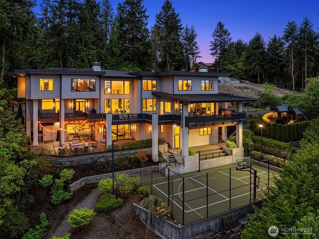 209 Northside Rd, Bellevue, WA 98004 - back of property at dusk featuring stucco siding, fence, a garden, and a balcony