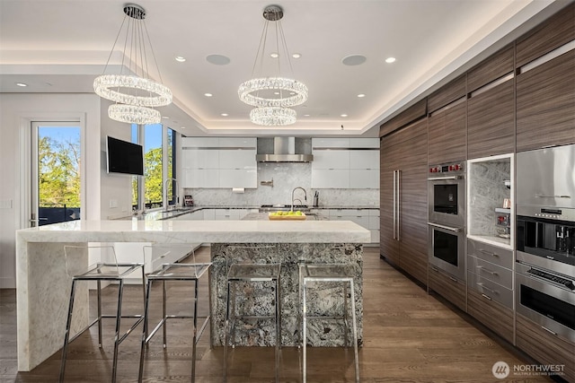 209 Northside Rd, Bellevue, WA 98004 - kitchen featuring stainless steel double oven, wall chimney exhaust hood, a chandelier, modern cabinets, and a sink