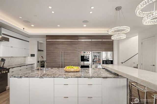 209 Northside Rd, Bellevue, WA 98004 - kitchen featuring modern cabinets, a chandelier, stainless steel double oven, a sink, and tasteful backsplash