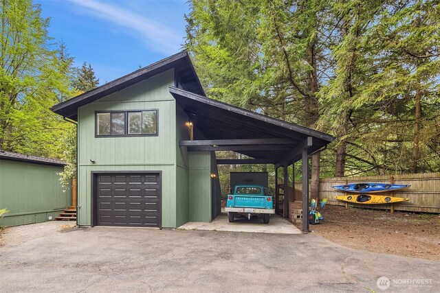view of property exterior with an attached garage, aphalt driveway, fence, and a carport
