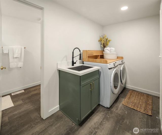 washroom with visible vents, a sink, baseboards, dark wood-style floors, and separate washer and dryer