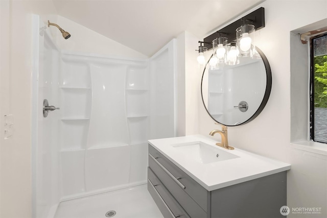 full bathroom with vanity, a stall shower, and lofted ceiling