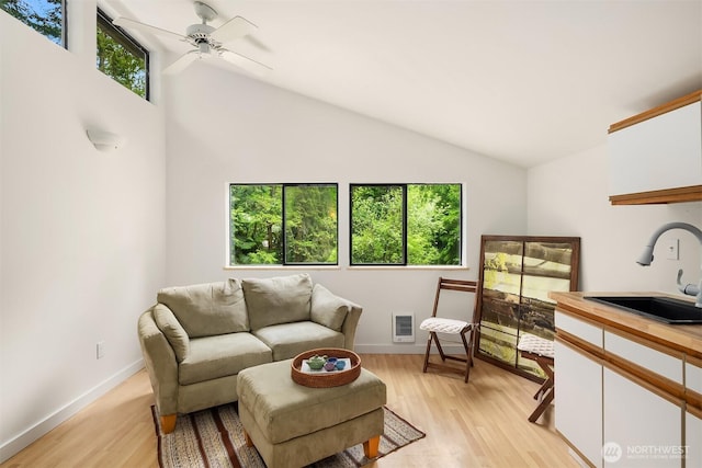 living area with a ceiling fan, a healthy amount of sunlight, lofted ceiling, and light wood-style floors