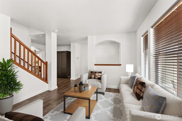 living area with stairway, baseboards, and wood finished floors