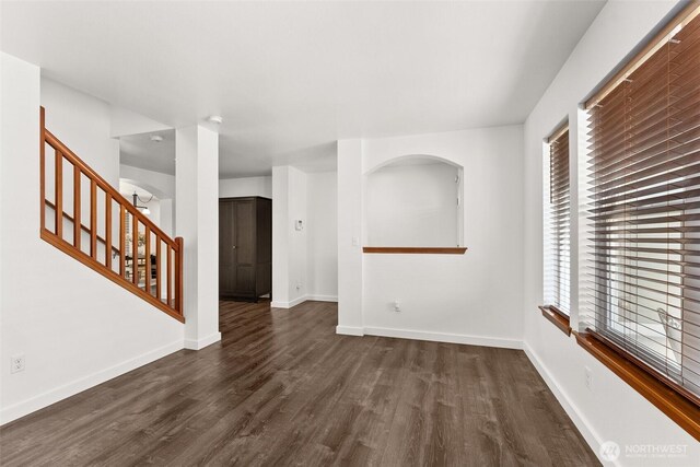 interior space featuring a healthy amount of sunlight, baseboards, dark wood-style floors, and stairs