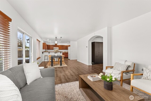 living room featuring recessed lighting, arched walkways, baseboards, and wood finished floors