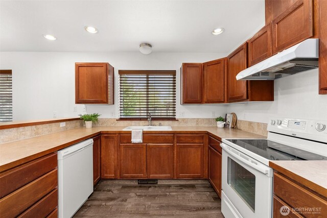 kitchen featuring a sink, white appliances, light countertops, dark wood-type flooring, and under cabinet range hood
