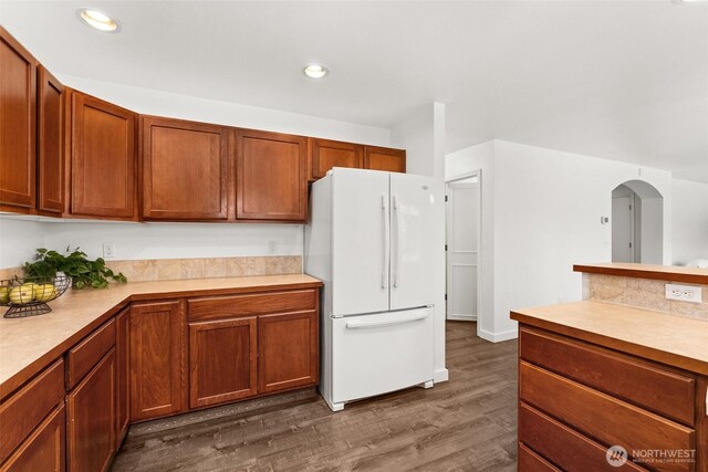 kitchen with brown cabinets, dark wood-style flooring, light countertops, freestanding refrigerator, and recessed lighting