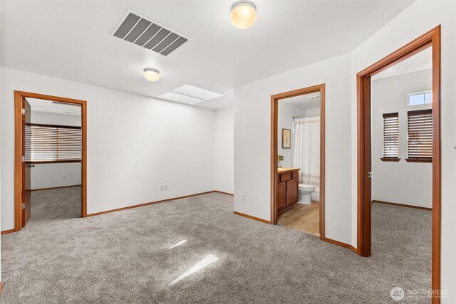 unfurnished bedroom with a spacious closet, multiple windows, carpet flooring, and visible vents