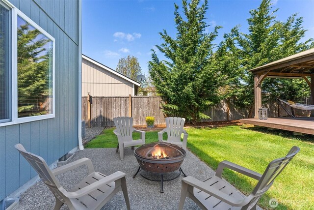 view of patio featuring an outdoor fire pit, fence, and a deck